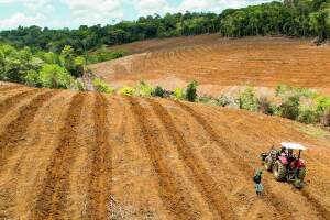 An image of a tractor from start-up Belterra and a farmer working on empty land. 