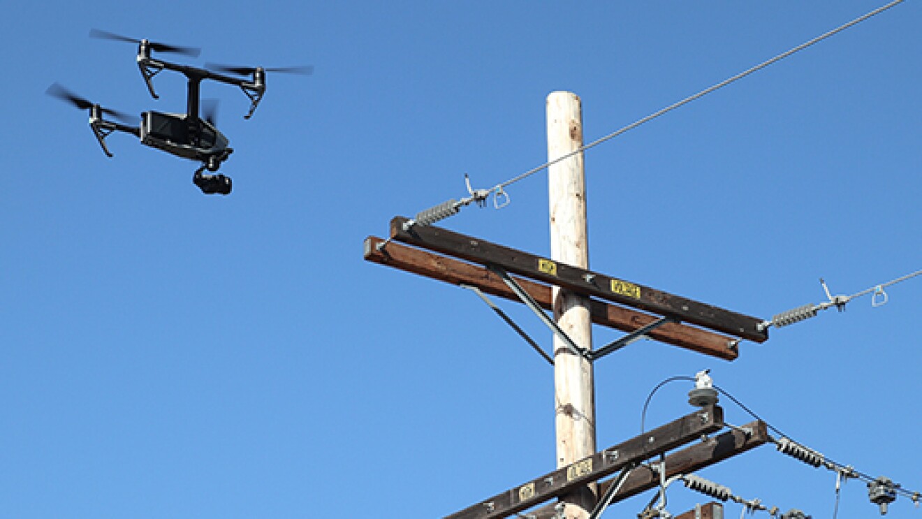 An image of a drone flying near a power line to capture video footage.