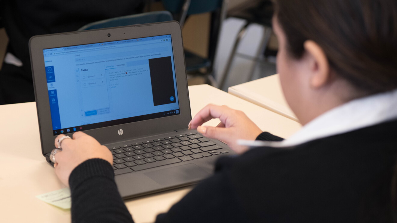 A teen girl types on a laptop computer