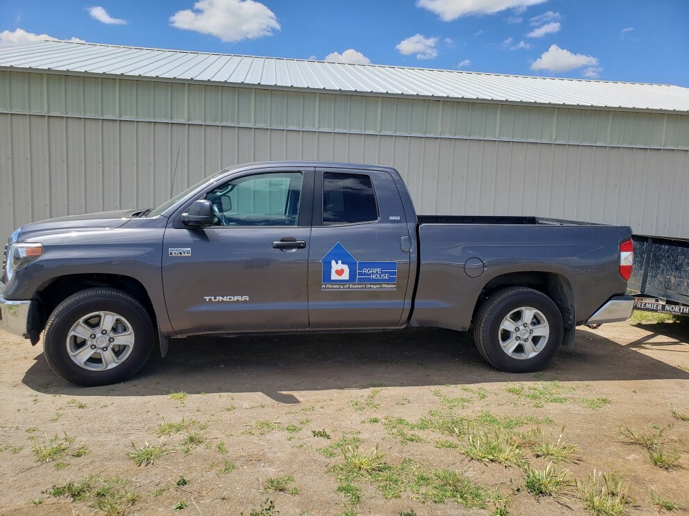 An image of a gray truck with a sticker on it that says "Agape House."