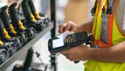 An Amazon employee disinfects a scanner next to a shelf of scanners.
