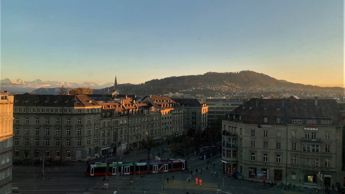 Ausblick auf die Innenstadt von Bern bei Sonnenaufgang. Im Hintergrund sind die Berge zu sehen.