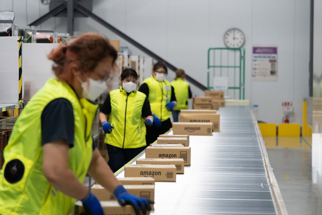 黄色いベストを着たAmazonのデリバリーステーションのスタッフたちが商品を仕分けしている