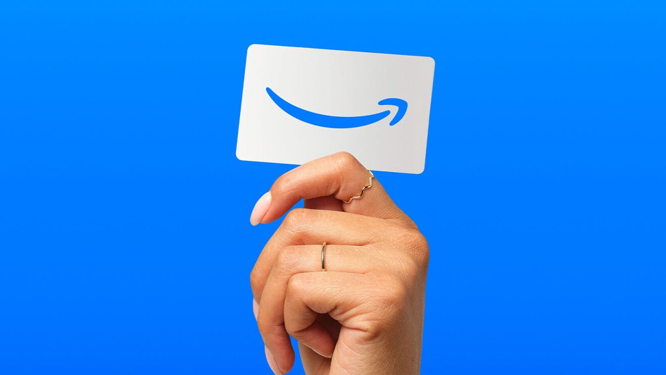 Hand holding Amazon gift card against blue background