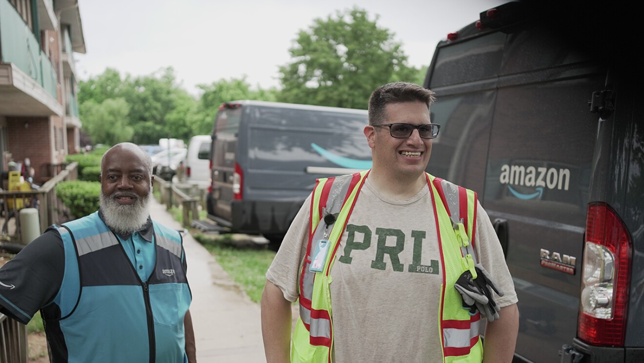 Volunteers and Amazon employees load up Amazon delivery vans with essential furniture and household products.