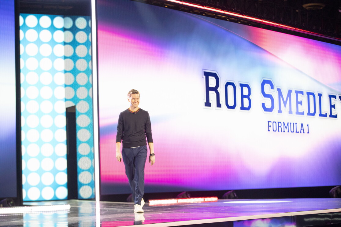 Rob Smedley, Formula 1 engineer standing on stage at the AWS re:Invent 2019 event. He is in front of a large screen with his name on it.