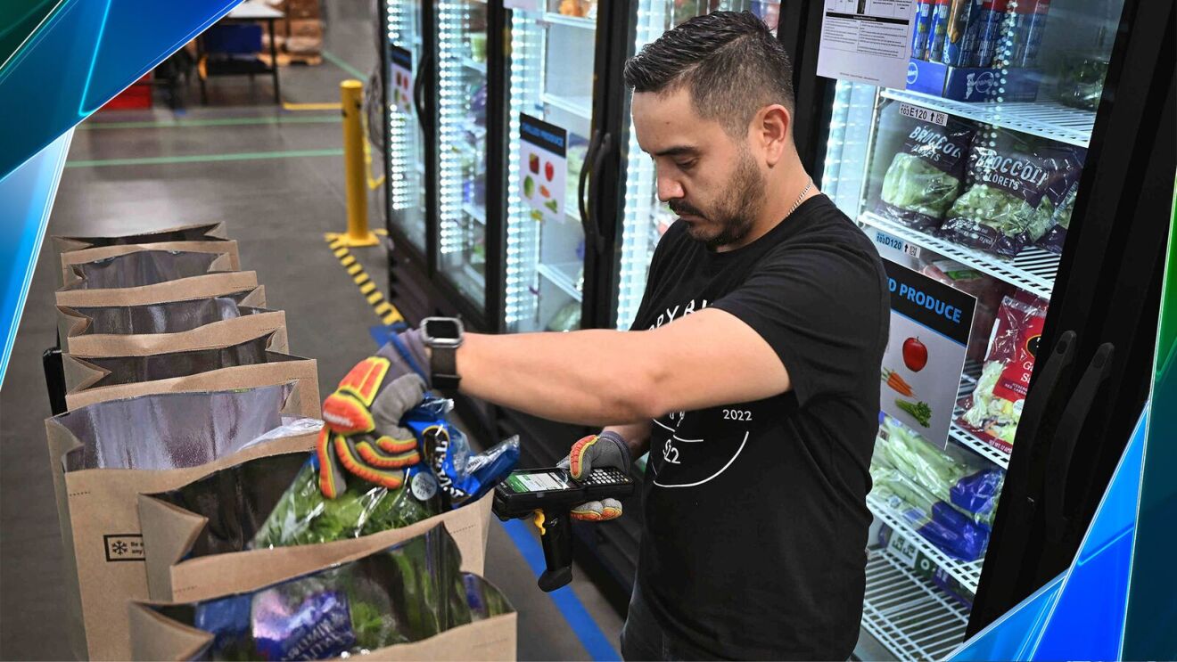 An Amazon employee packing grocery items at a fulfillment center.