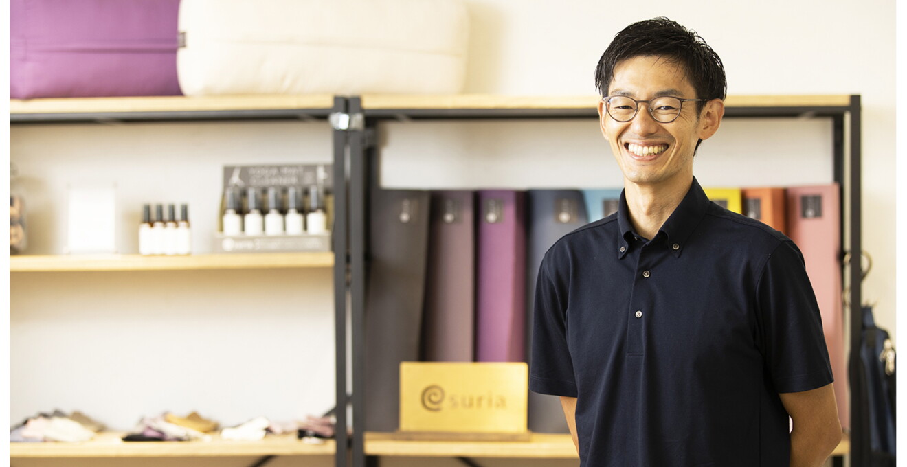 取扱製品を背景に、笑顔の石谷さん