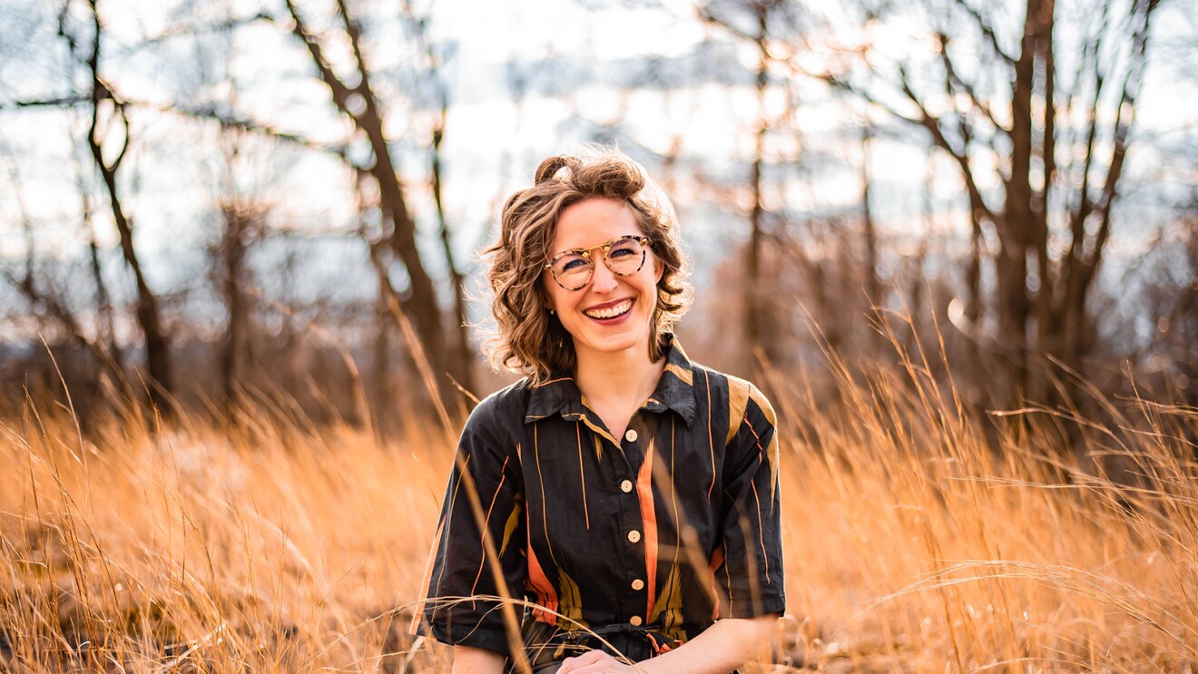 亚马逊音乐艺术家负责人Katie (schlosser) vitolins的专业形象。她坐在田野里微笑着拍照片。