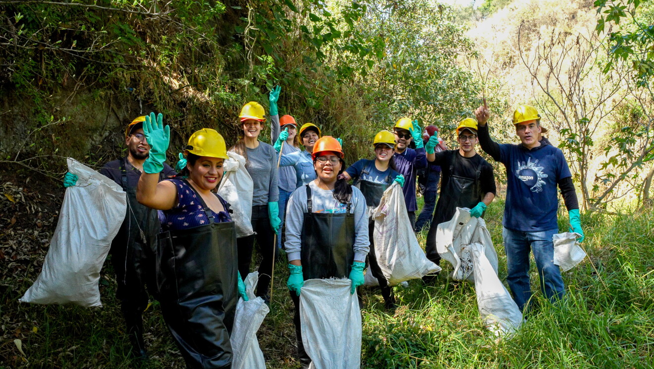 Acción conjunta entre Amazon y la NGO Rios Tarango. Foto de equipo con las bolsas de basura en la limpieza de Tarango. 