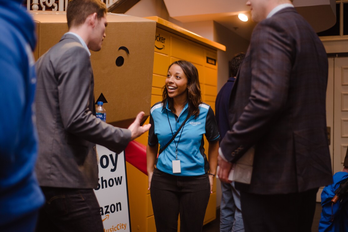 A woman wearing an Amazon-branded shirt speaks with two men at an event in Nashville.