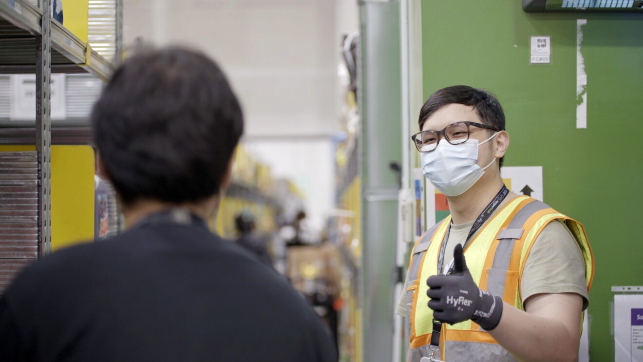 Amazon associate Bryan Chua is seen giving a thumbs up to his colleague at Amazon's Fulfillment Center in Singapore