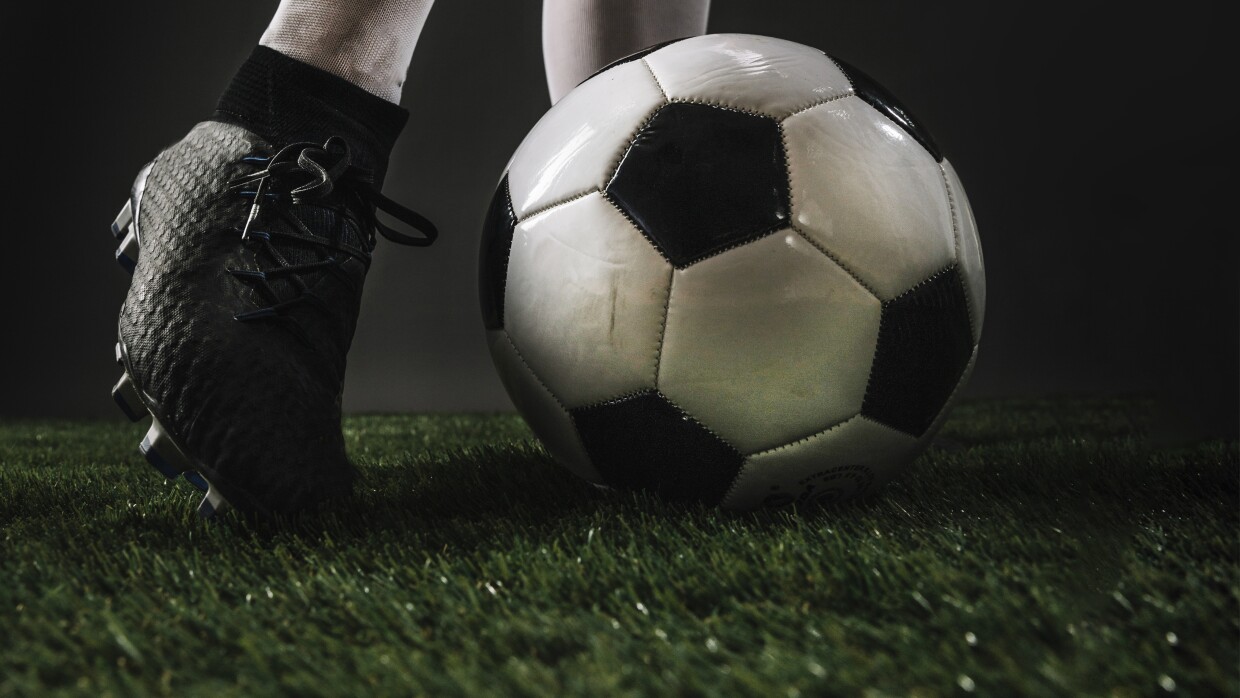 crop-legs-kicking-ball-grass