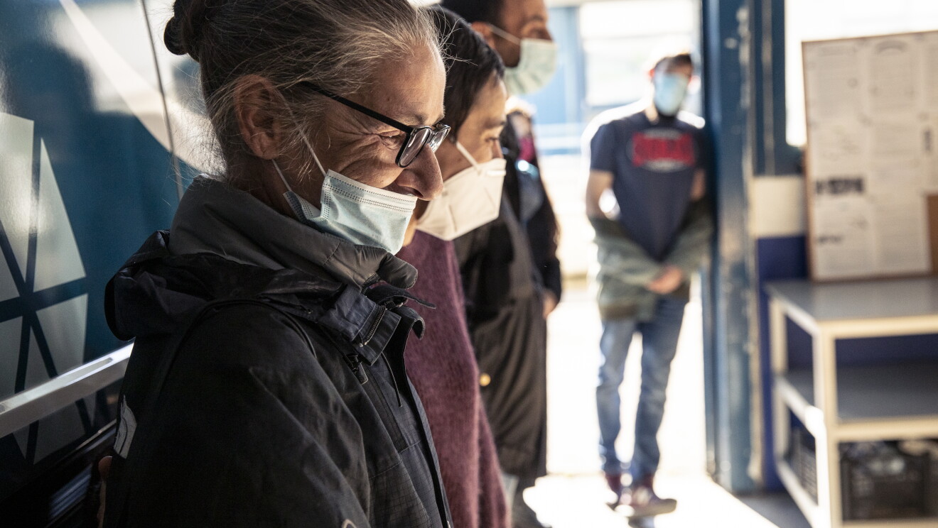 Centro de día para personas sin hogar Casablanca de Alcobendas. Una furgoneta de Amazon está dentro de un garaje. En primer plano aparecn cuatro usuarios del centro, todos ellos con mascarilla y mirando en la misma dirección. 