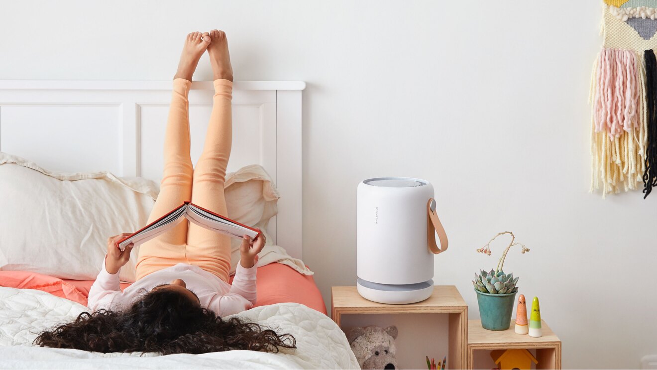 一个女孩躺在床上,读一本书,她的脚靠在墙上。