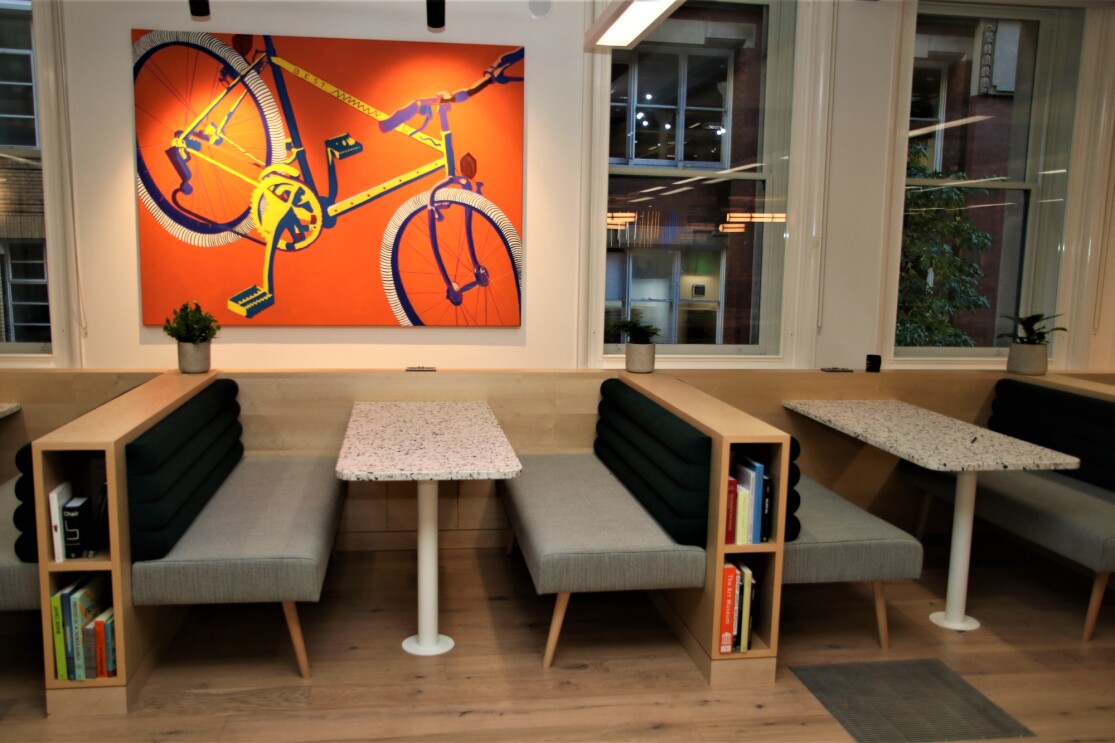 A minimalist lounge in Amazon's Manchester office, with built-in bookshelves and bicycle art