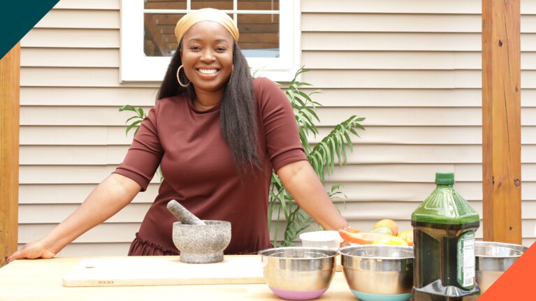 A photo of Toyin Kolawole, founder & CEO of Iya Foods, standing behind a table that includes cooking ingredients on it.