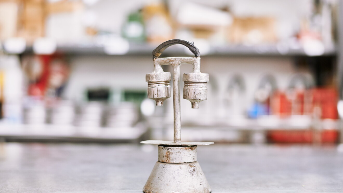 Foto di un prototipo di Kamira, piuttosto ossidato, composto da pezzi di varie caffettiere rimontati da Nino Santoro. Questo ha due bocchette per far uscire il caffé e un manico ad arco nella parte superiore.