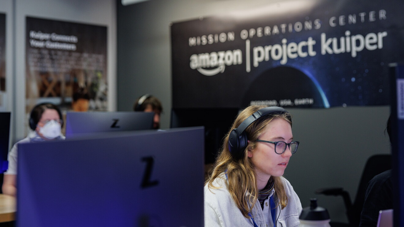 An image of a person from Project Kuiper’s mission management team working on a computer with others working in the background.