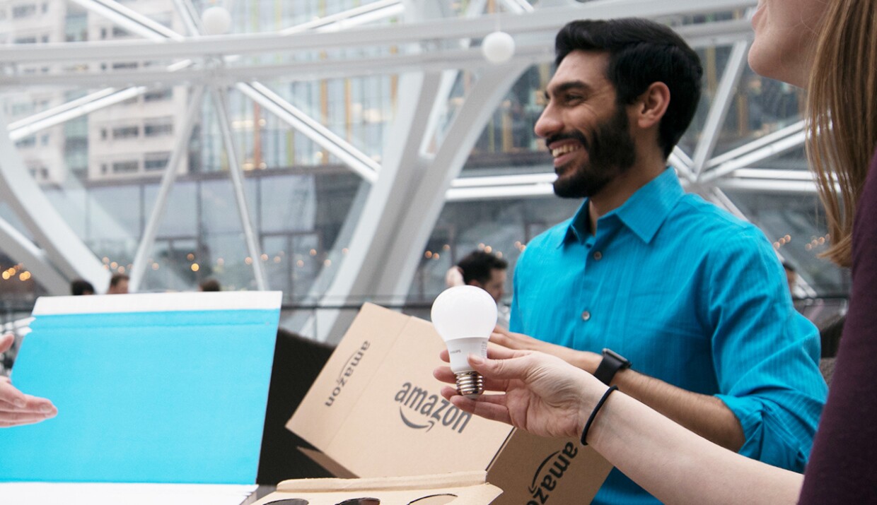 Three Amazon employees discuss the packaging of a light bulb.
