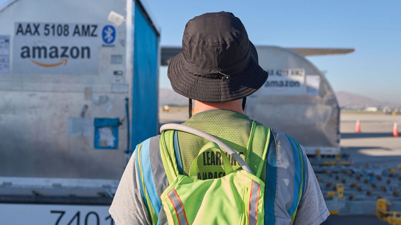 Ground crew member observing Amazon Air freight aircraft during daylight operations