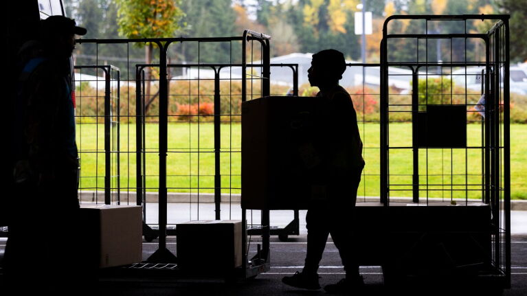 Silhouette of person carrying a package by delivery carts