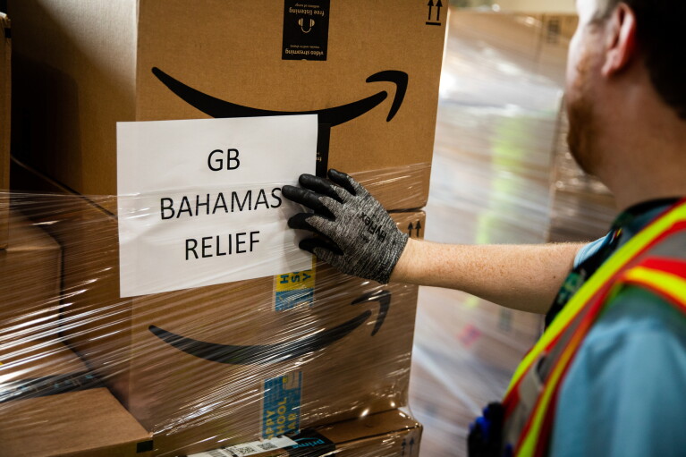 Image of man checking a label on a stack of boxes being sent for the Bahama Relief initiative