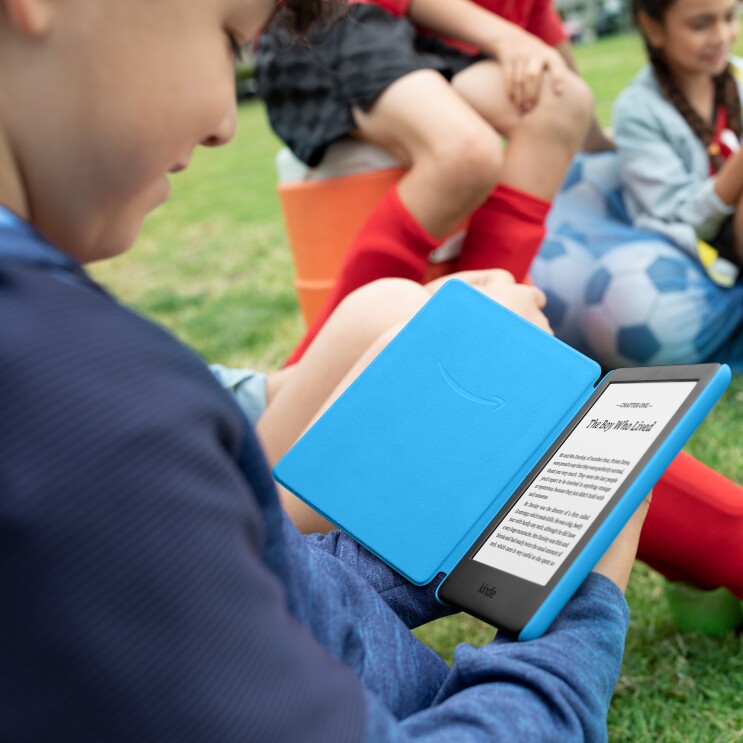 Child reading a book at the park on the Amazon Kindle Kids Edition