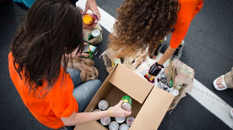 people in orange shirts moving canned food into boxes