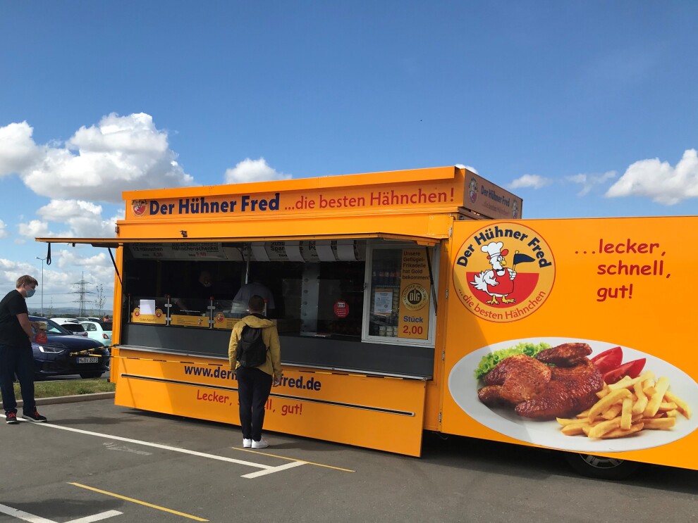 Ein gelber Food Truck mit Hühnerspeisen.