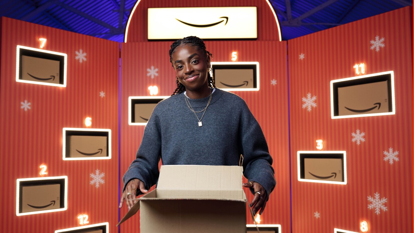 Cat Burns opening an amazon parcel surrounded by Amazon parcels in a festive background setting