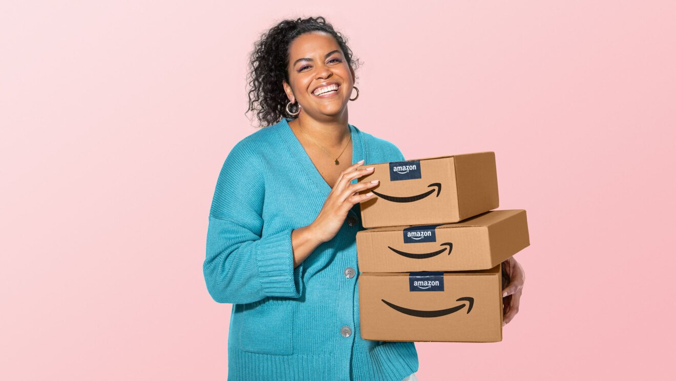 eine Frau hält amazon-Pakete vor einem rosa Hintergrund