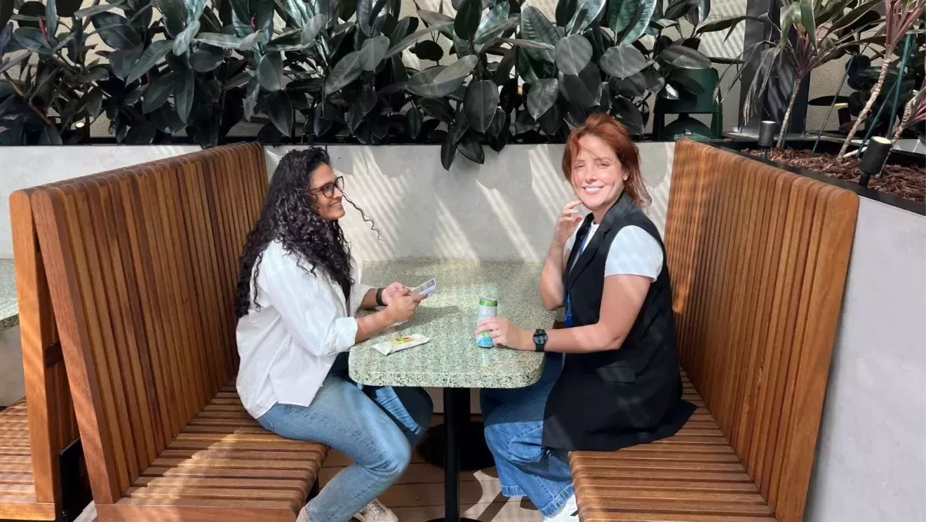 向かい合わせになった木製のベンチに座る女性2人