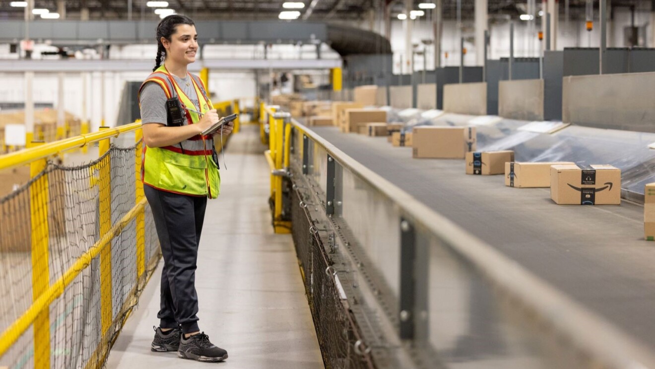 Amazon employee in a safety vest inspecting Amazon package processing