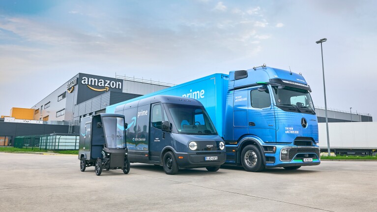 Amazon Prime delivery vehicles of various sizes parked in front of warehouse