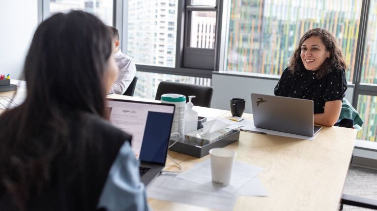 An image of two women having a conversation in a conference room setting.