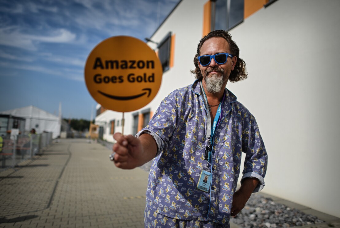 Amazon Mitarbeiter im Schlafanzug mit Amazon Goes Gold Schild