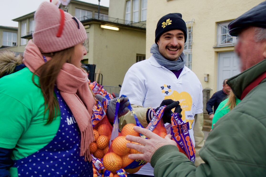 Eine Frau und ein Mann verteilen lebensmittel an einen älteren Herren.