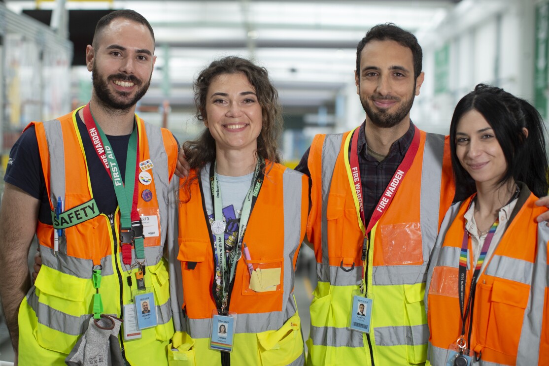 Team safety DLO1: four young men and women in orange vests are smiling at the camera