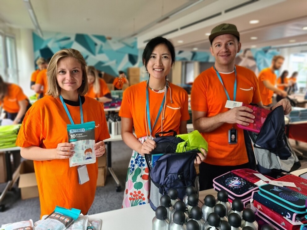 Amazon Mitarbeiter:innen, die sich sozial bei der Aktion "Back to school" engagieren und an einem Packtisch stehen.