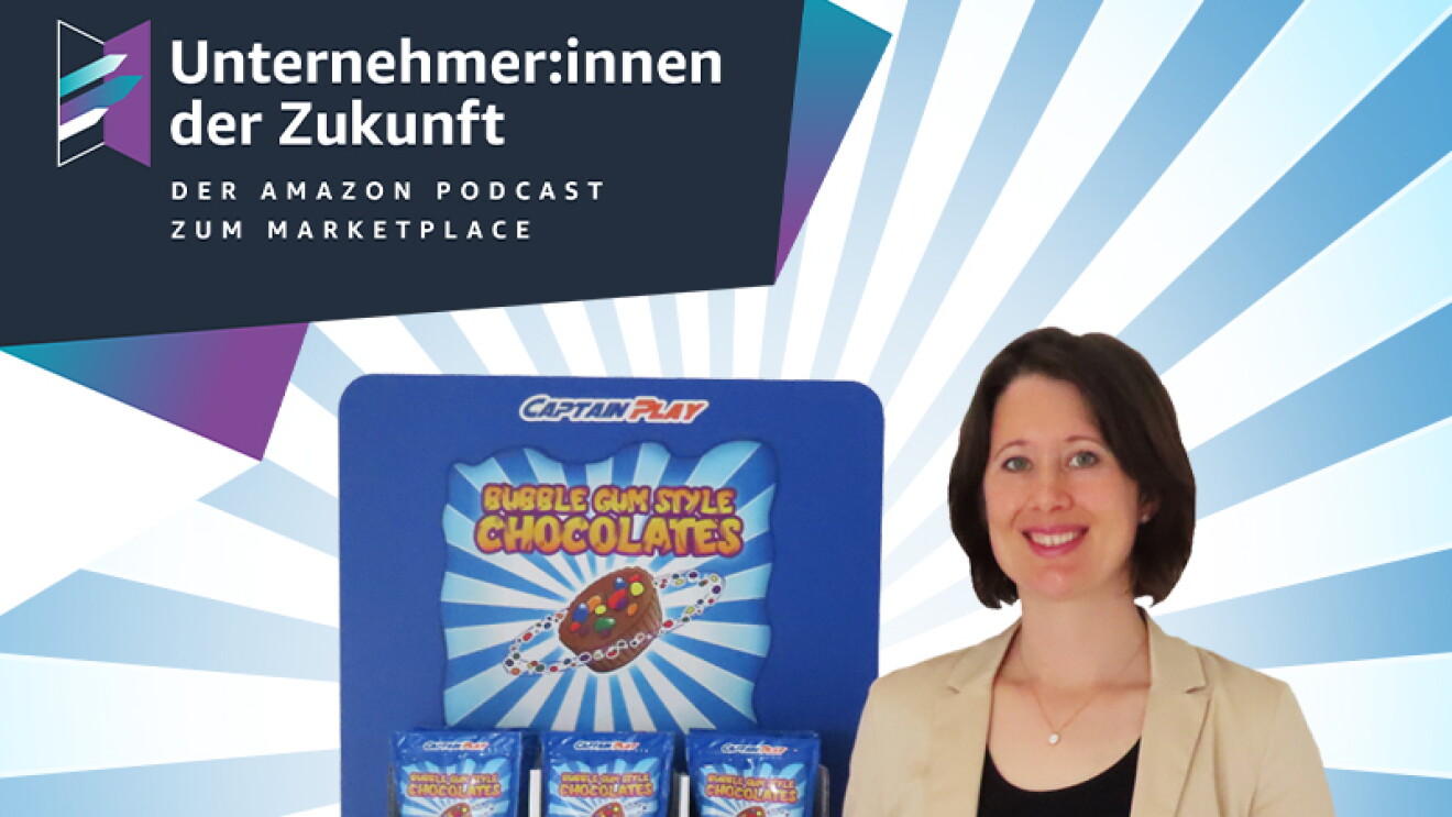 Annika Würtenberger, Gründerin von Captain Play, steht neben einem Süßigkeitenregal. Sie trägt einen beigen Blazer und ein schwarzes Shirt. Sie hat braune, halblange Haare und lächelt in die Kamera. In der Hand hält sie eine Tüte mit Süßigkeiten. 