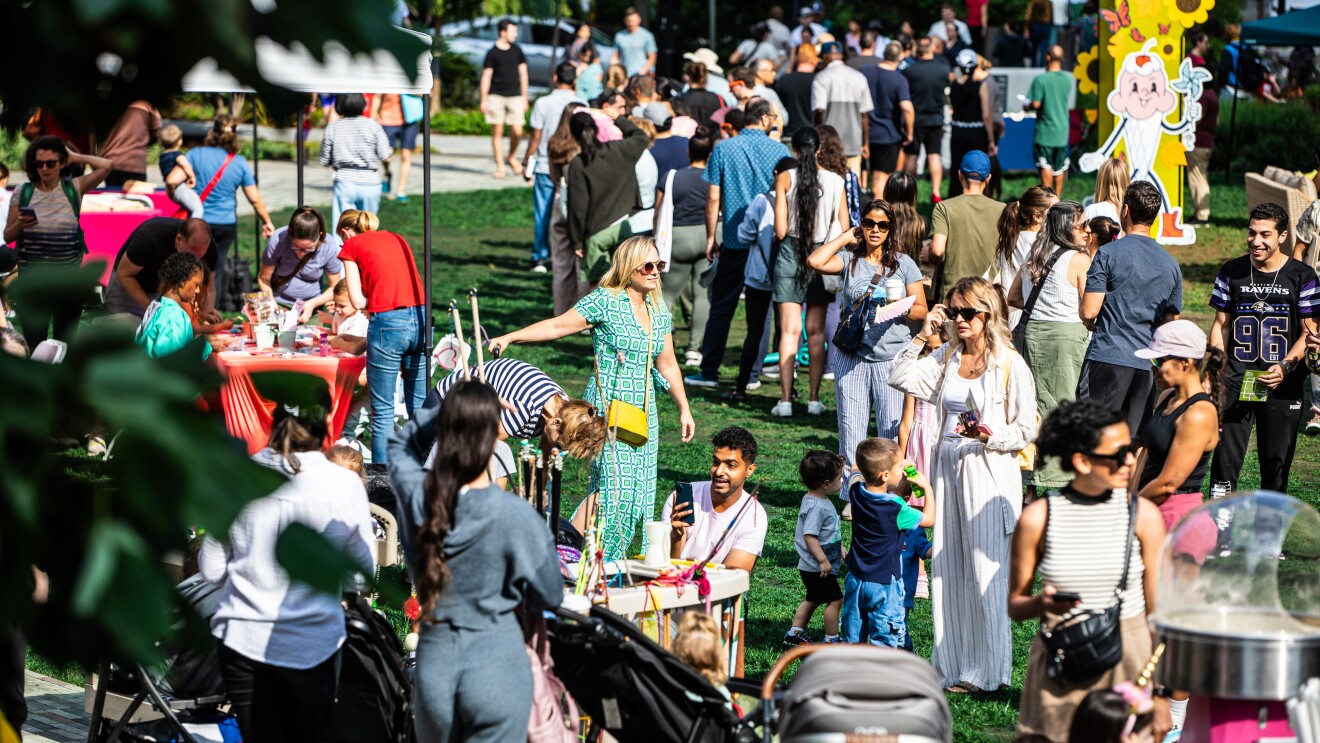 Amazon's HQ2 Community Day: Bustling community event in a park with food stands and colorful decorations