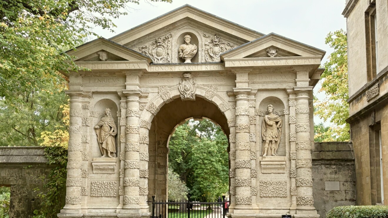 Ornate stone arch with classical sculptures and Latin inscriptions