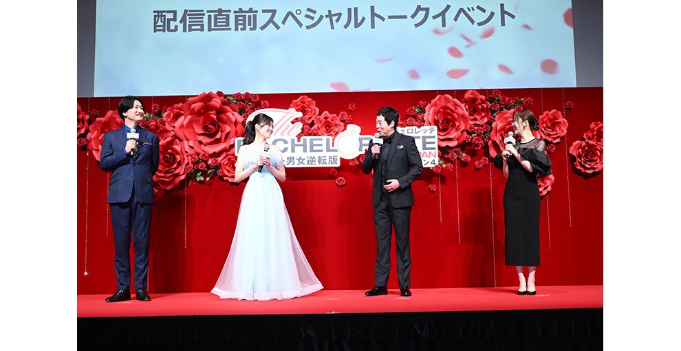 赤いバラの花の大きなオブジェと生花の赤いバラが飾られた赤い壁を背に並んで立つ4人の人物。情報のスクリーンに「配信直前スペシャルトークイベント」の文字。