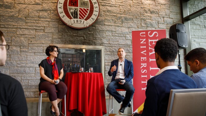 一个女人,Roshanak Roshandel坐在了椅子上,旁边的一个男人,安迪雅西,领导一个在西雅图大学炉边谈话。