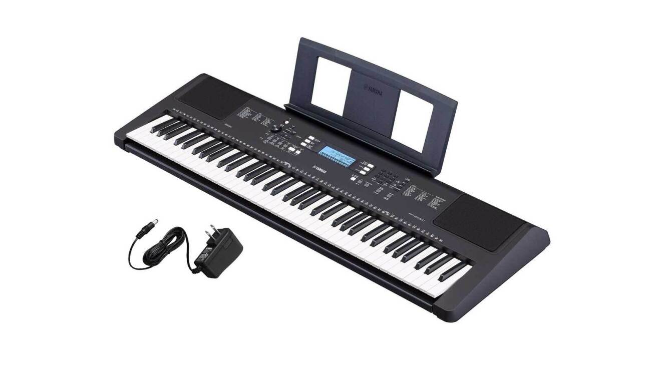 An image of an electric piano keyboard from Yamaha. It comes with a stand for your music notes at the top and a charging cord.