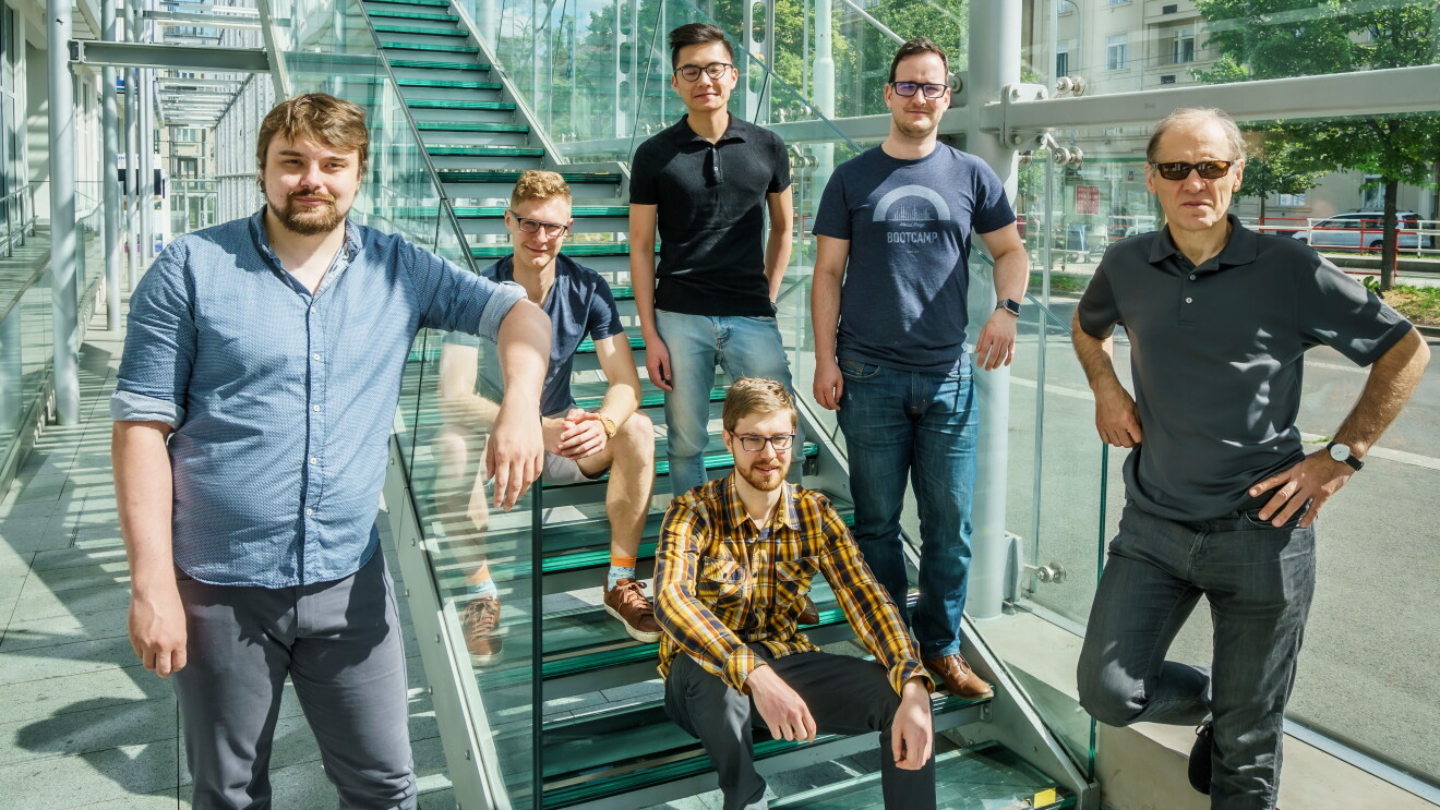 A group of six men pose on stairs.