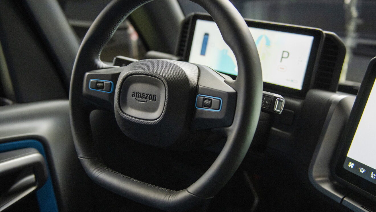 A steering wheel with the Amazon logo includes built-in microphones and speakers.