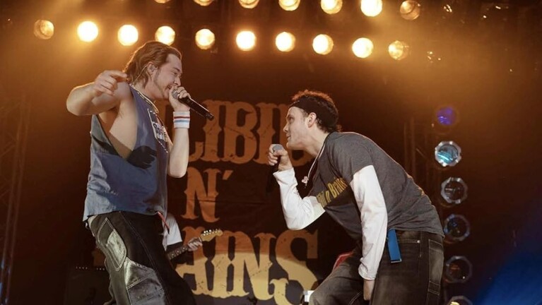 Two men with microphones perform on stage