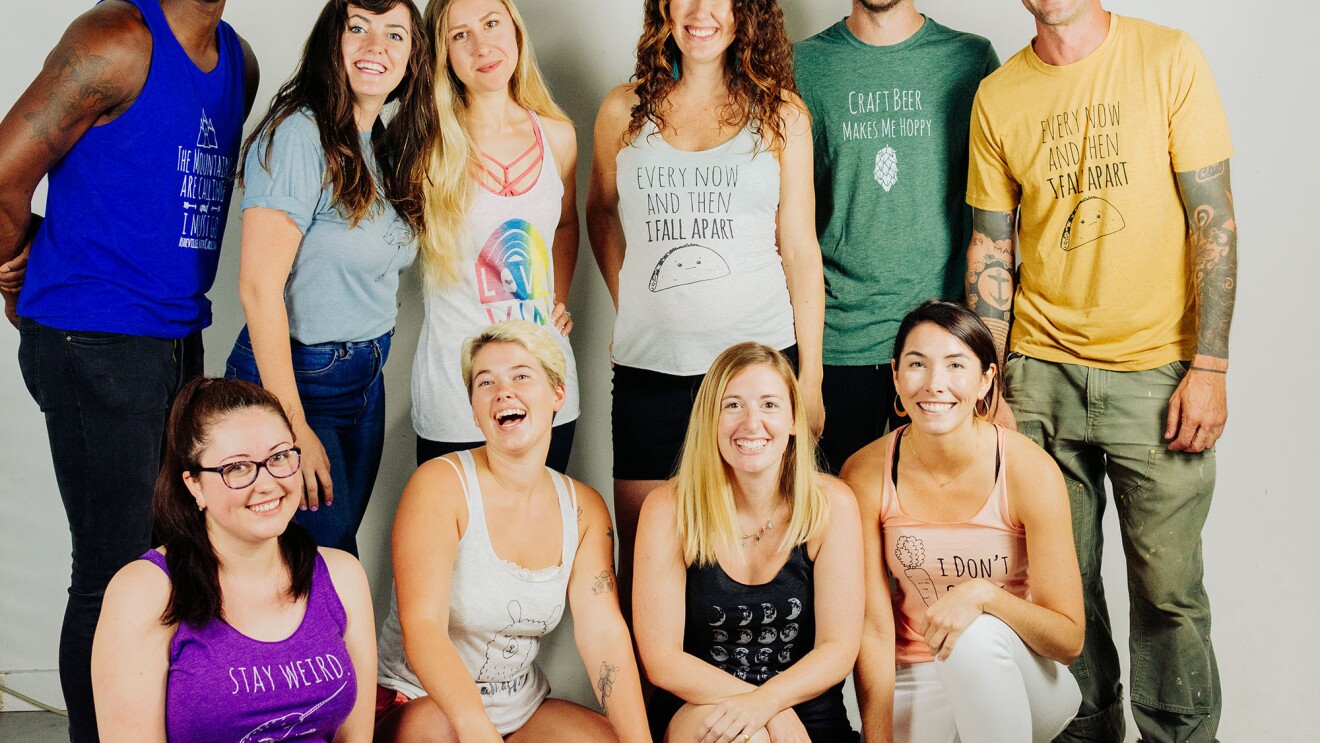 Ten young adults gather together for a posed photograph, smiling at the camera.